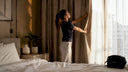 Traveler adjusting curtains in hotel room