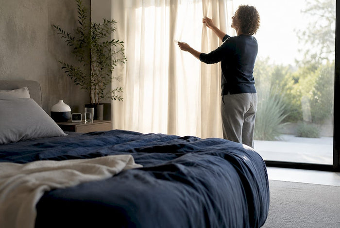 Person adjusting sleep-optimized bedroom curtains