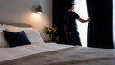 Man adjusting curtains in bedroom for sleep