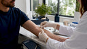 Hands applying transdermal drug patch on forearm
