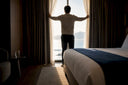 Traveler opening curtains to morning light