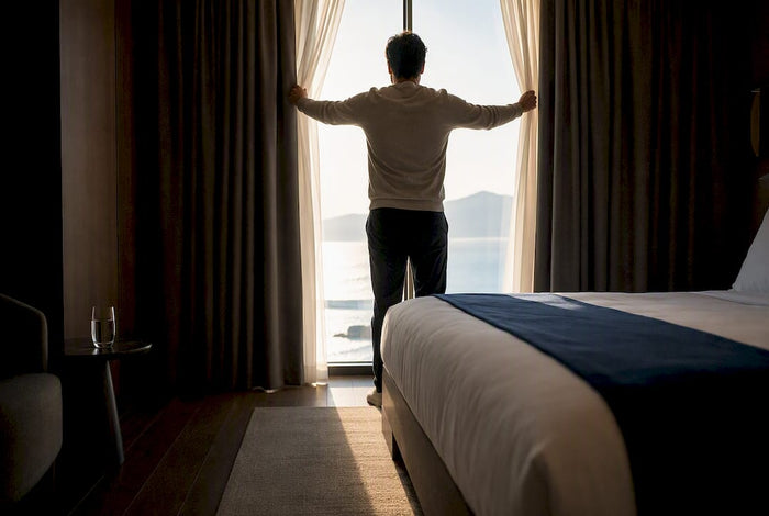 Traveler opening curtains to morning light