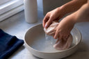 Hands gently washing a silk mask cover