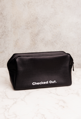Black toiletry bag with 'Checked Out.' text on a light gray background